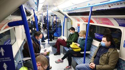 People wearing protective face masks commute in a Victoria line underground train in London. Reuters