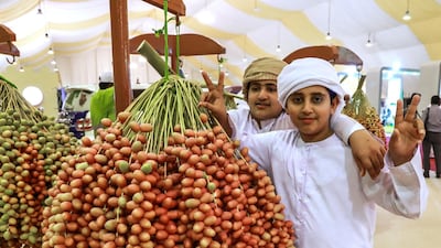 Young visitors pose beside bunches of dates. Victor Besa / The National