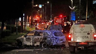 Israeli border police vehicles drive past an extinguished burnt vehicle in Lod near Tel Aviv, after rockets were launched towards Israel from the Gaza Strip controlled by the Palestinian Hamas movement. AFP