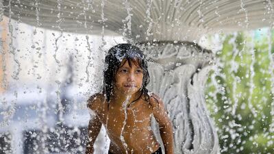 A child seeks respite from the summer heat in a water fountain at a park in Manila, Philippines. AP Photo