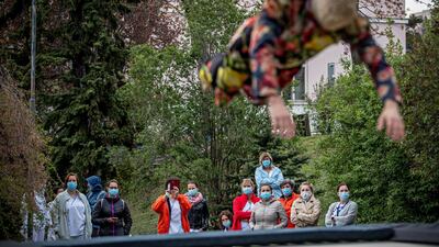 Health workers wearing protective face masks watch a member of the contemporary circus company Cirk La Putyka performing at the courtyard of a hospital in Prague, Czech Republic. EPA