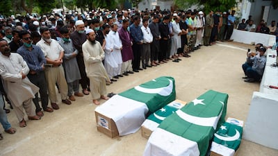 Mourners offer funeral prayers beside the coffins of four members of the same family who died in the crash in Karachi. AFP