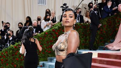 Simone Ashley, in a black skirt with a gold crop top by Moschino. AFP