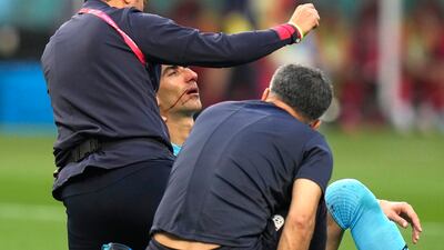 Iran's Beiranvand is attended to by team support staff after being injured. Photo: AP