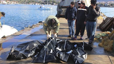 The bodies of migrants who drowned trying to reach Greece are examined at a port near Izmir, Turkey, on January 21, 2016. The coast guard said 12 migrants died after a boat capsized in rough weather. IHA via Associated Press