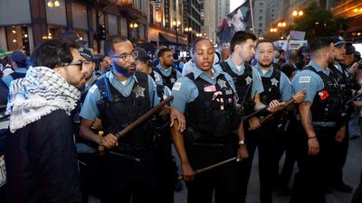 Police officers stand guard as people protest against federal immigration sweeps in Chicago. Reuters