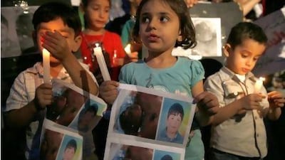 Syrian children carry pictures of 13-year-old Hamza al Khatib and hold candles during a protest in front of the United Nations building in Beirut. Jamal Saidi / Reuters