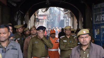 Indian police officers stand guard as rescue workers move toward the site where a fire broke out in New Delhi, India. According to news report, at least 40 people were killed after a fire broke out at a building in New Delhi's Anaj Mandi area on the morning of 08 December. EPA