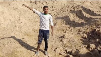 Khalaf Luhaibi, a shepherd who reported seeing ISIL carry out executions at a base in the northern Iraqi town of Hawija, stands next to bones and scraps of clothing at the site. Kirkuk Governor's Office via AP
