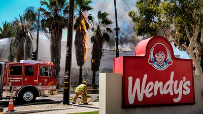 A palm tree is ablaze as Los Angeles firefighters battle a building fire, in the Panorama City area of LA, California. AP