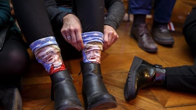 A supporter of US Democratic presidential candidate Hillary Clinton adjusts her socks baring the image of Hillary Clinton as she watches results on a TV screen during the US election night party in Geneva, Switzerland. Salvatore Di Nolfi / EPA