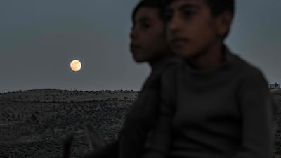 Children ride a donkey as the waxing gibbous moon rises in the countryside of the village of Tal Sallur in the rebel-held Afrin region of Syria's northern Aleppo province, a day ahead of the June "strawberry supermoon". AFP