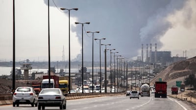 A thick plume of smoke billows as motorists drive their vehicles along a highway near the source of an explosion at the Shahid Rajaee port. AFP