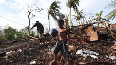 A young boy kicks a ball as his father searches through the rubble of their family home in Vanuatu’s capital Port Vila after Cyclone Pam ripped through the island nation. Dave Hunt / AFP Photo