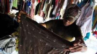 A young woman picks through a pile of used clothes in East Timor. The clothes come from all over the world and though they're meant as charity they don't help local tailors who say they can't compete with the prices.