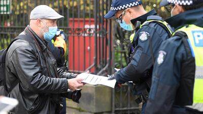 A press photographer has his work permit checked by police during an anti-lockdown protest in Melbourne, Australia. EPA