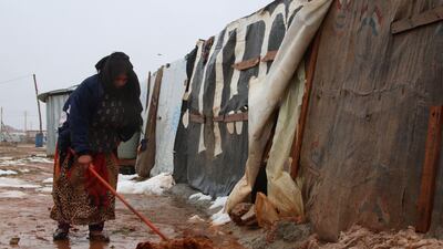 A Syrian refugee shovels mud in front of a makeshift shelter follwoing rain storms in Bekaa valley. AFP