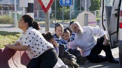 An ultra-Orthodox Jewish man huddles with his three sons and a daughter outside their car in the southern Israeli town of Kiryat Malachai as a red alert sounds signalling a rocket attack.