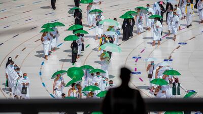 A Saudi security officer watches as pilgrims circumambulate the Kaaba