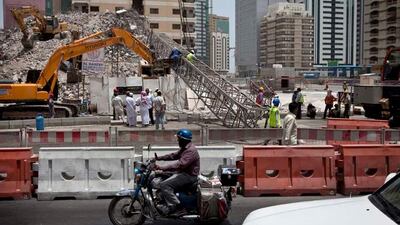 Construction workers work away to clean up remains of a crane that collapsed earlier that morning on Tuesday, July 12, 2011, during the morning rush hour in downtown Abu Dhabi. No one was hurt and only road blocks and the crane itself suffered damages. (Silvia Razgova/The National)