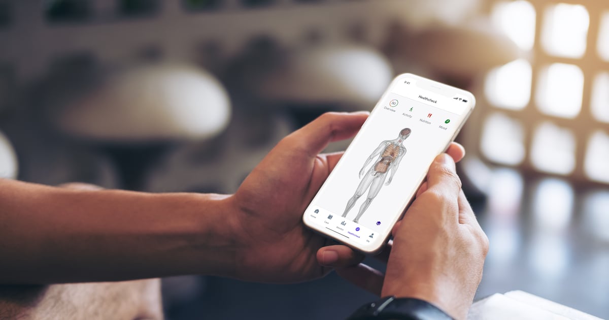 A person holds a phone displaying Babylon’s Healthcheck interface and body diagram.