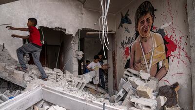 Palestinian children pass a mural in Deir Al Balah. Residents created murals and set up displays of Israeli missiles and fragments to draw attention to the damage to their homes. AP