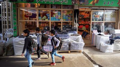Iraqi boys walk past a shop in a local market in the northern city of Mosul on November 21, 2018. AFP