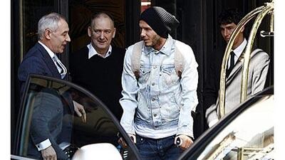 Beckham leaves the hotel on crutches with his father Ted, second left, in downtown Milan today.