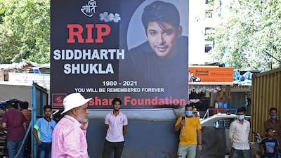 People stand in front of a poster of Indian actor Sidharth Shukla, a day after his demise in Mumbai on September 3, 2021. AFP