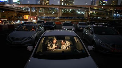 A couple look at a mobile phone as they sit in a car at a screening at a drive-through cinema in Seoul. AFP