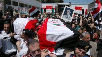Syrian military police carry coffins as they prepare to send the bodies of 11 soldiers and security force members to their families for burial in the city of Homs.