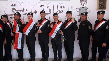 Iraqi policemen holding national flags queue to vote shortly after polling stations opened for parliamentary elections, in Baghdad. EPA