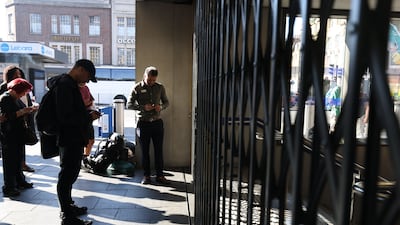 Passengers wait for Kings Cross St Pancras underground station in London to open. PA