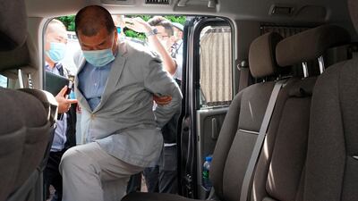 Hong Kong media tycoon Jimmy Lai, who founded the local newspaper 'Apple Daily', gets into a car after being arrested by police officers at his home. AP Photo