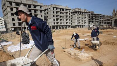 Workers sift through the soil and use wheelbarrows to remove piles of dirt at the site. AFP