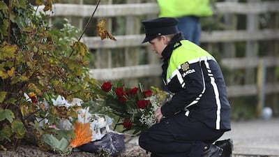 An Irish police officer lays flowers she was given by a member of the public at the scene of the explosion. PA