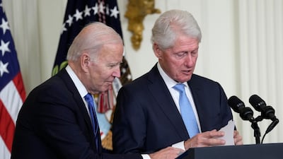 President Joe Biden helps former president Bill Clinton find his notes at an event in the East Room of the White House in Washington on Thursday. AP