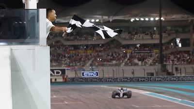 Will Smith waves the checkered flag as Mercedes' British driver Lewis Hamilton crosses the finish line during the Abu Dhabi Formula One Grand Prix at the Yas Marina Circuit yesterday.AFP