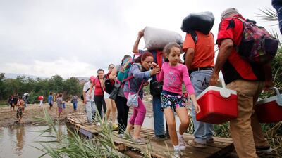People cross a makeshift bridge in the Tachira River, from Venezuela into Colombia, near the Simon Bolivar International bridge on March 12, 2019. AP