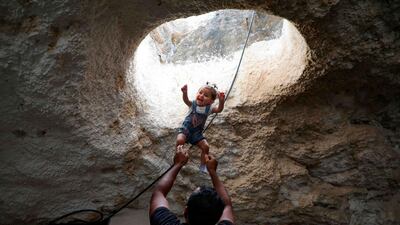 Ahmed Amarneh throws his daughter beneath a skylight hole as they play together at his home. AFP