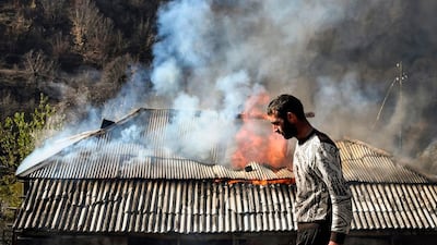A man walks past a house burning in the village of Charektar outside the town of Kalbajar. Villagers in Nagorno-Karabakh set their houses on fire before fleeing to Armenia. AFP
