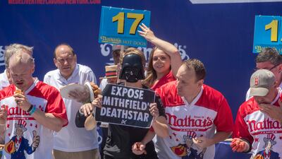 About 17 hot dogs into the contest, a protester jumps on the stage. EPA