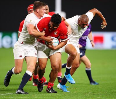 Siua Maile of Tonga is tackled by England's Owen Farrell during the Rugby World Cup Group C game on Sunday. Maile was working as a roofer when he received the call-up to play for his country. Getty