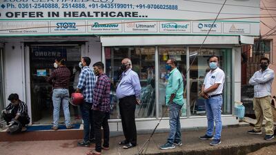 Masked customers line up outside a pharmacy to buy medicines in Guwahati. AP