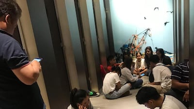 People sitting in the Terminal 21 shopping mall in Nakhon Ratchasima as they wait to be evacuated to a safer area following a shooting incident in the mall. AFP