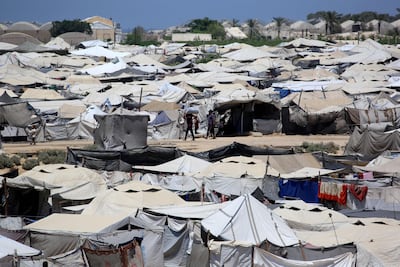 Internally displaced Palestinians walk past hundreds of tents in Gaza. AFP