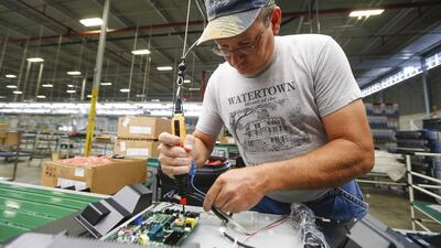 A worker uses an electronic screwdriver to install the motherboard on the reverse side of an Element television. Element's plant in South Carolina has six assembly lines making 32- and 40-inch TVs that are now available in all of Walmart’s more than 4,000 US stores. Chris Keane / Reuters