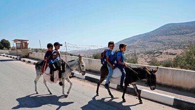 Palestinian students ride on a donkey in the village of Al-qaba in the Jordan Valley as they head to school about five kilometres away from their homes. AFP