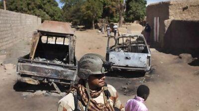 A French soldier stands guard in front of charred pickup trucks used by Islamist rebels in Diabaly.