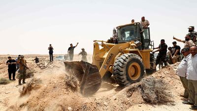 People cheer as an excavator removes rubble during the reopening of a 300-kilometre section of road between the cities of Misrata and Sirte. AFP